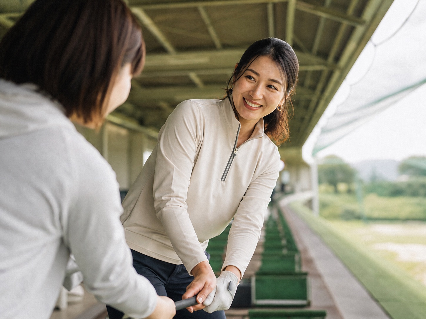 初心者にクラブの握り方をやさしく教える女性コーチ